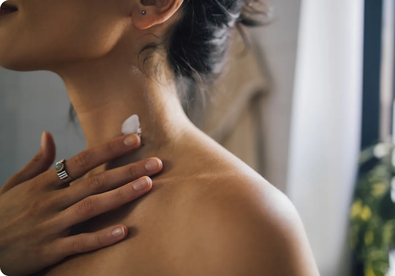Close-up of a person's shoulder as they apply a bit of cream.