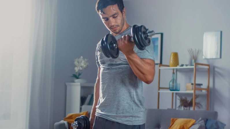 Seorang pria sedang bersepeda statis dalam garasi