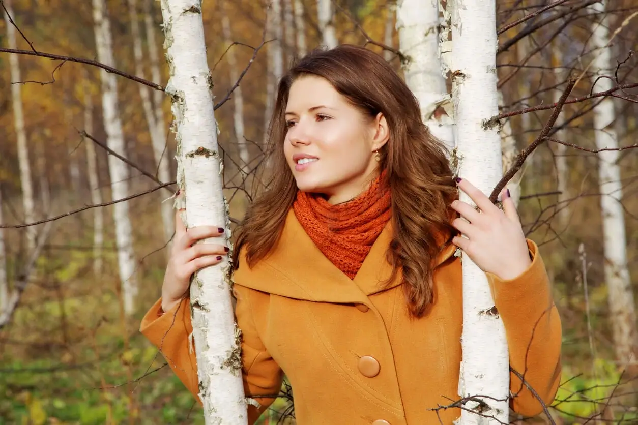 Pani stojąca między drzewami, ciesząc się brakiem objawów alergii