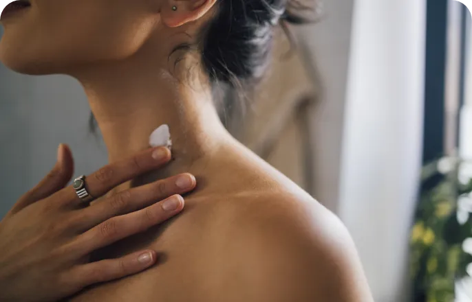 Close-up of a person's shoulder as they apply a bit of cream.