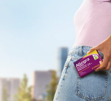 Woman holding a box of Allegra 24 hours allergy relief in urban setting