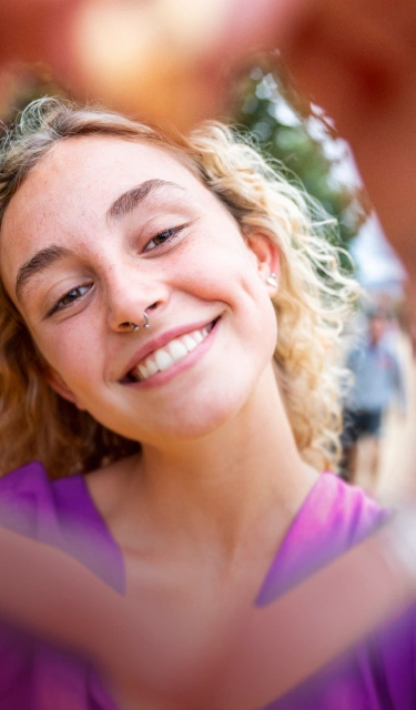 Happy woman making a heart shape with her hands, suggesting allergy relief and enjoying life outdoors.